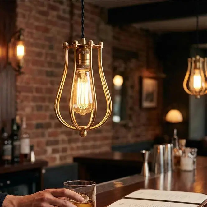 Person holding a glass of whiskey at a bar with warm lighting and a brick wall.