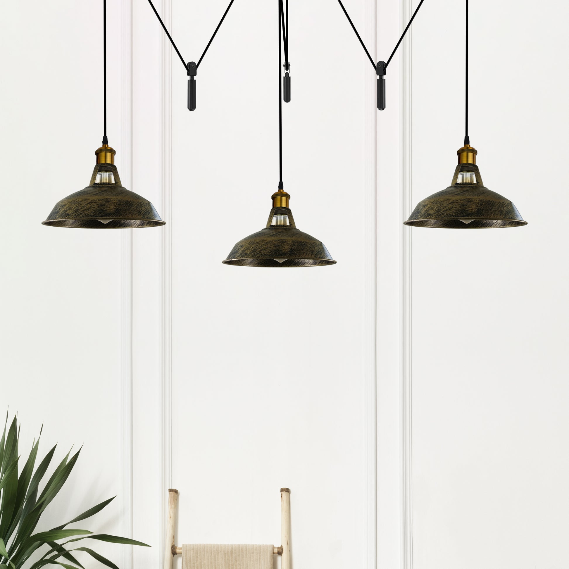 A three-headed industrial spider pendant light in brushed brass finish on black cable